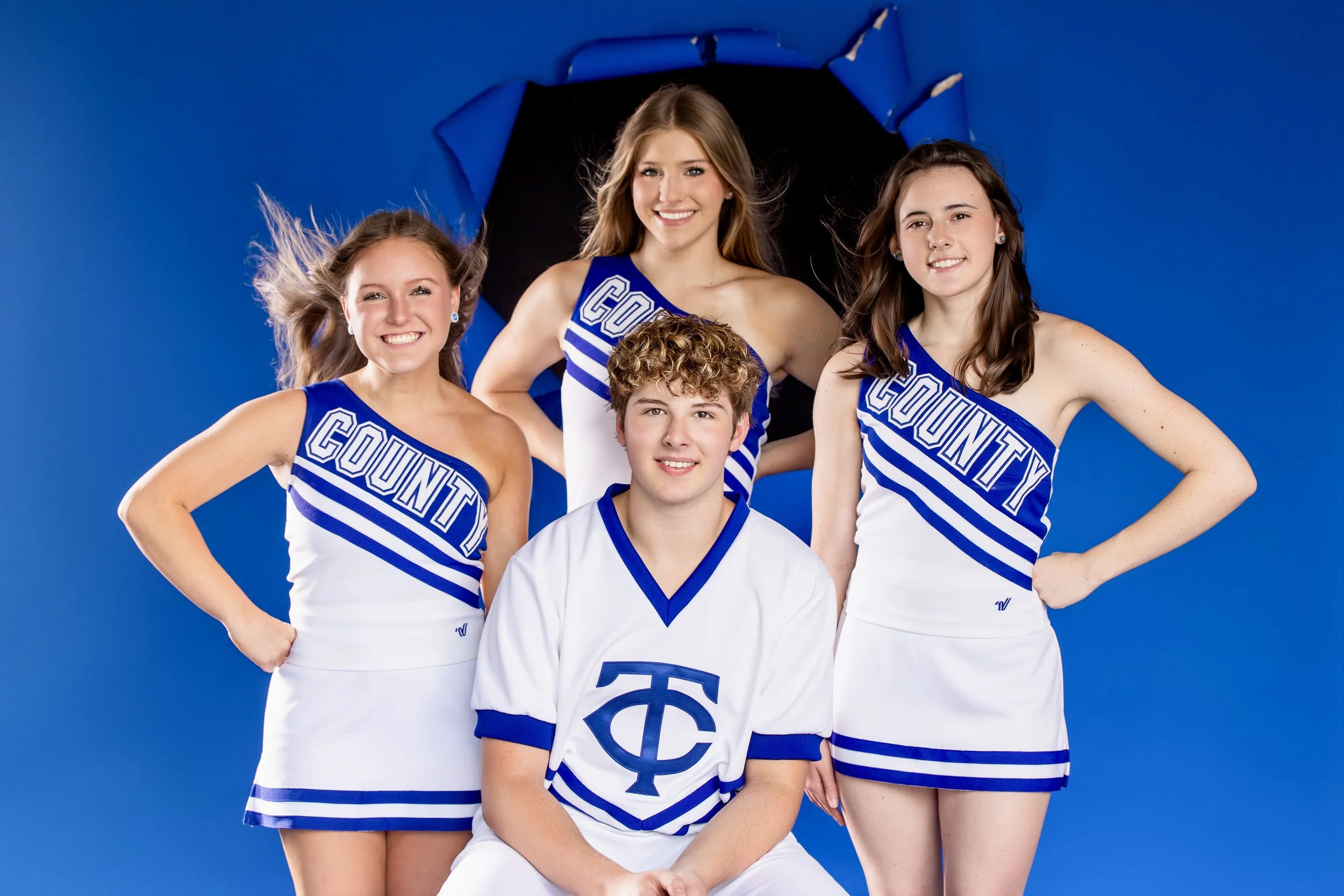 Four Tuscaloosa County cheerleaders and a football player posed together under a black umbrella in the studio.